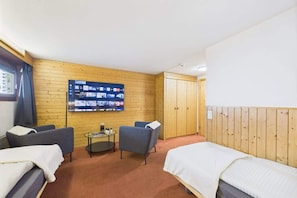 Een hotelkamer met twee bedden, een aan de muur bevestigde televisie, een klein tafeltje en een houten paneelwand.