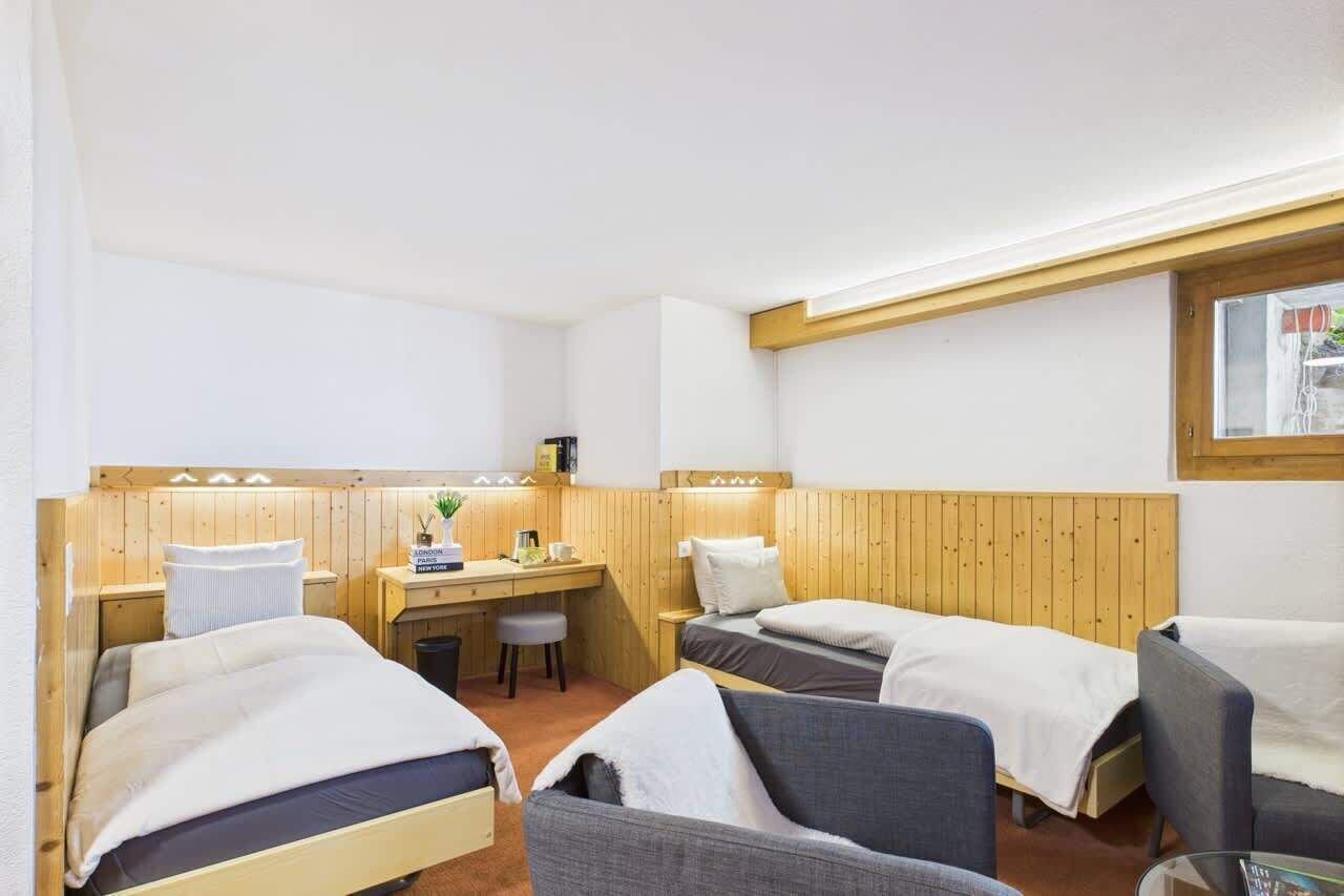 Une chambre avec deux lits, un bureau, une chaise et une fenêtre.