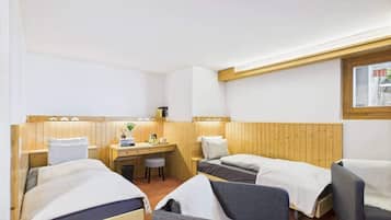 Une chambre avec deux lits, un bureau, une chaise et une fenêtre.
