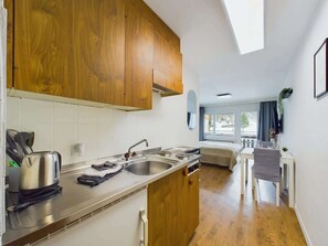 Una cucina compatta con mobili in legno, un lavello in acciaio inossidabile e una zona pranzo con tavolo e sedia.