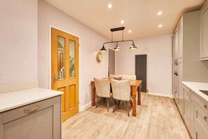 A kitchen with a dining table, chairs, a clock, and cabinets. - Host & Stay | The Mews (Rothbury)