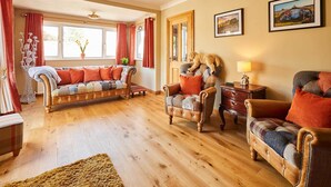 A cozy living room with a sofa, armchairs, and a wooden floor. - Host & Stay | The Mews (Rothbury)