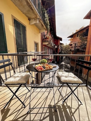Ein Balkon mit Tisch für zwei Personen, ausgestattet mit einer Käseplatte, Trauben und Weingläsern.