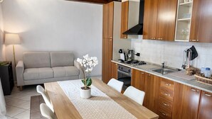 A kitchen with wooden cabinets, a dining table with chairs, a stove, and a sink. - Casa Renoir: A bright one-bedroom apartment in the historic center of Suna, near the lake and the beach  (Suna)