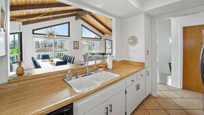 A modern kitchen with wooden countertops, a large sink, and a view of a dining area. - 25% Off Sept 3-6! Mins 2 Beach, Rooftop Patio View (Oxnard)