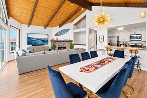 A modern living space with a dining area, a fireplace, and a kitchen.