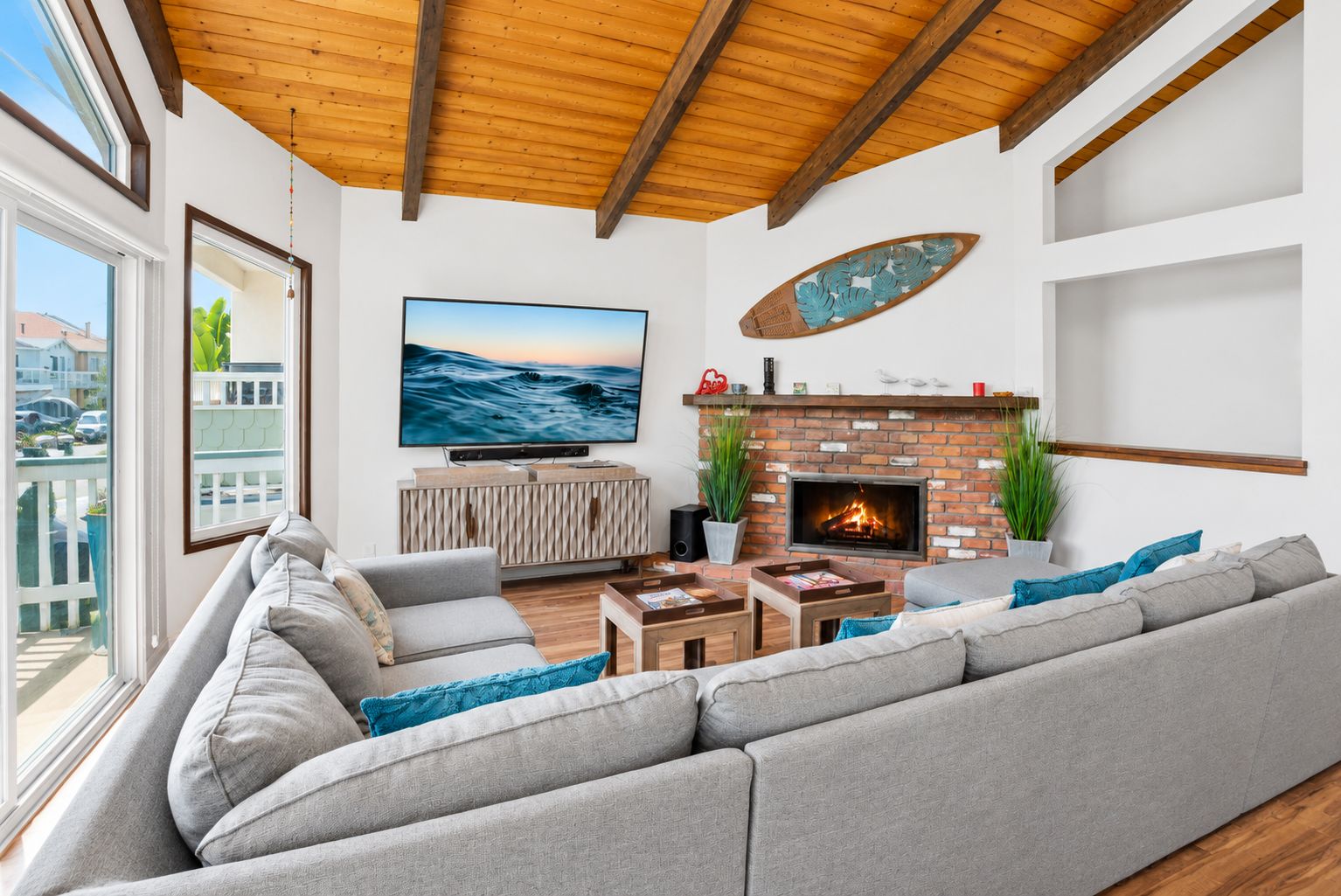 A modern living room with a large gray sectional sofa, a fireplace, and a television mounted on the wall.