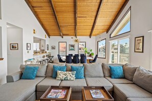 Ein modernes Wohnzimmer mit Holzboden, einer Sofagarnitur und einem Essbereich mit Stühlen und einem Tisch.