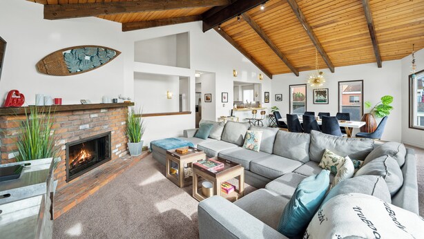 A spacious living room with a fireplace, a large sofa, and a dining area with chairs. - 25% Off Sept 3-6! Mins 2 Beach, Rooftop Patio View (Oxnard)