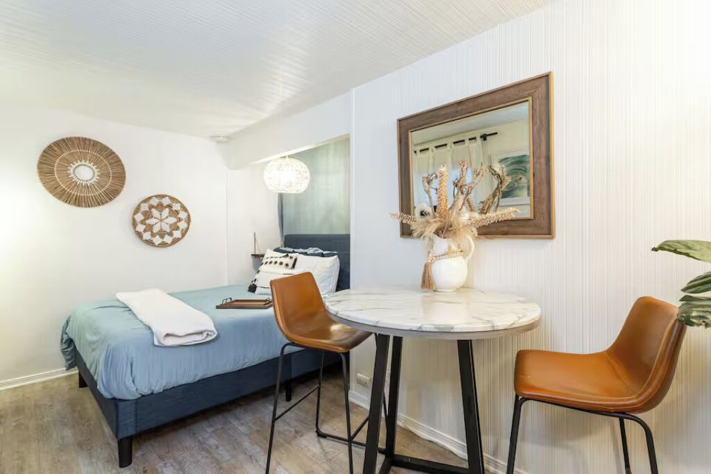 Ein Zimmer mit einem Bett, zwei Stühlen, einem runden Tisch, einem Spiegel und Wanddekorationen.