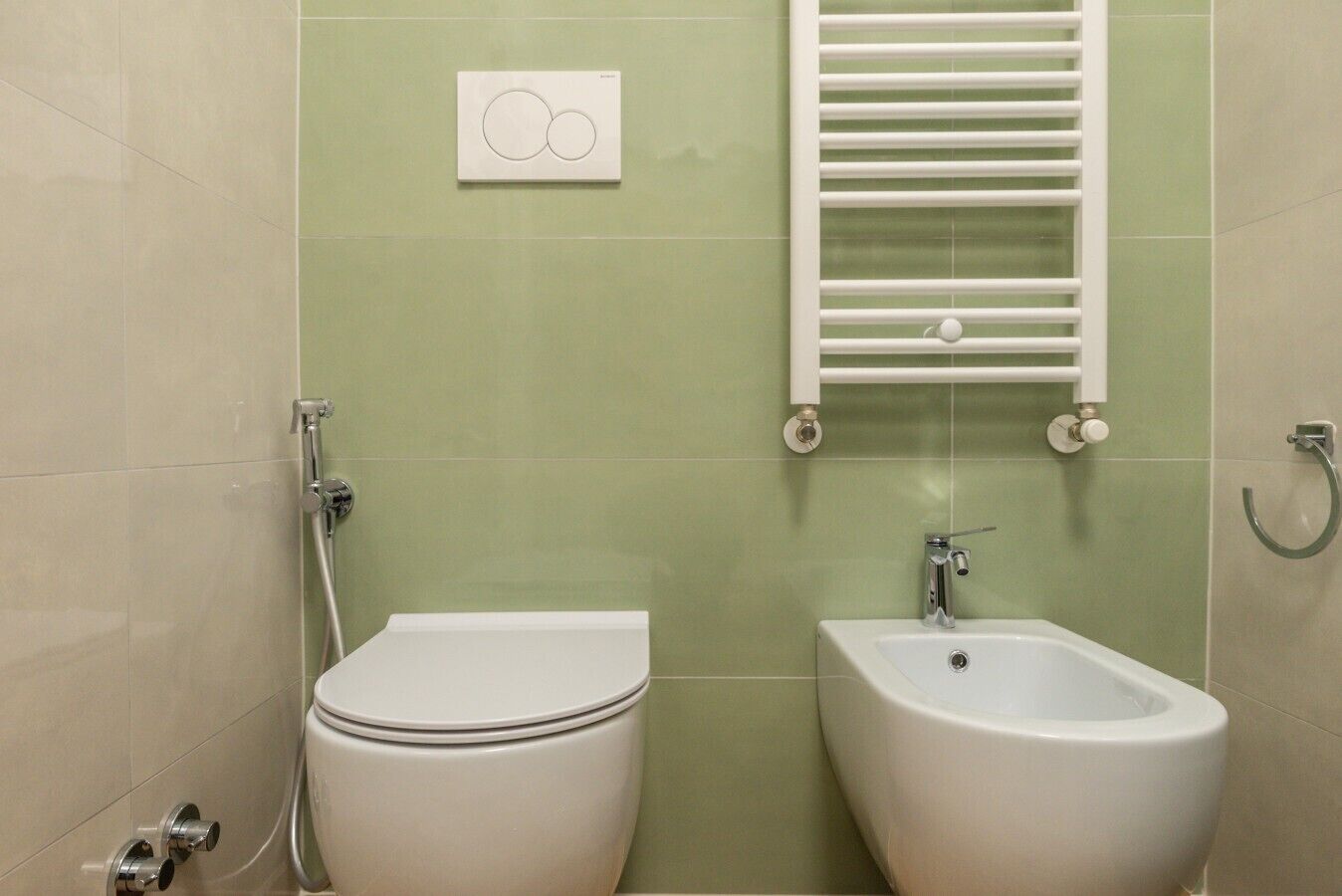 A bathroom with a toilet, bidet, and a towel rack.