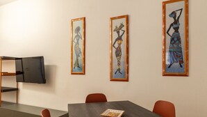 Un salón de conferencias con una mesa, sillas y tres obras de arte enmarcadas en la pared.