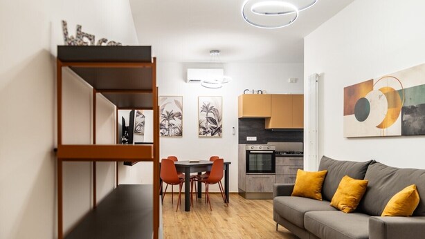 Un apartamento moderno con comedor, kitchenette y sala de estar con sofá y cojines.