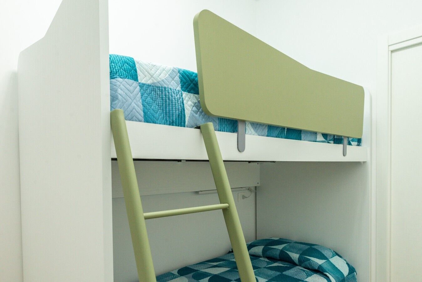 A bunk bed with a ladder, a pillow, and a wall-mounted shelf.