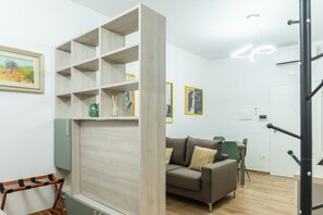 Una habitación con un sofá, una estantería de madera, un cuadro y una puerta.
