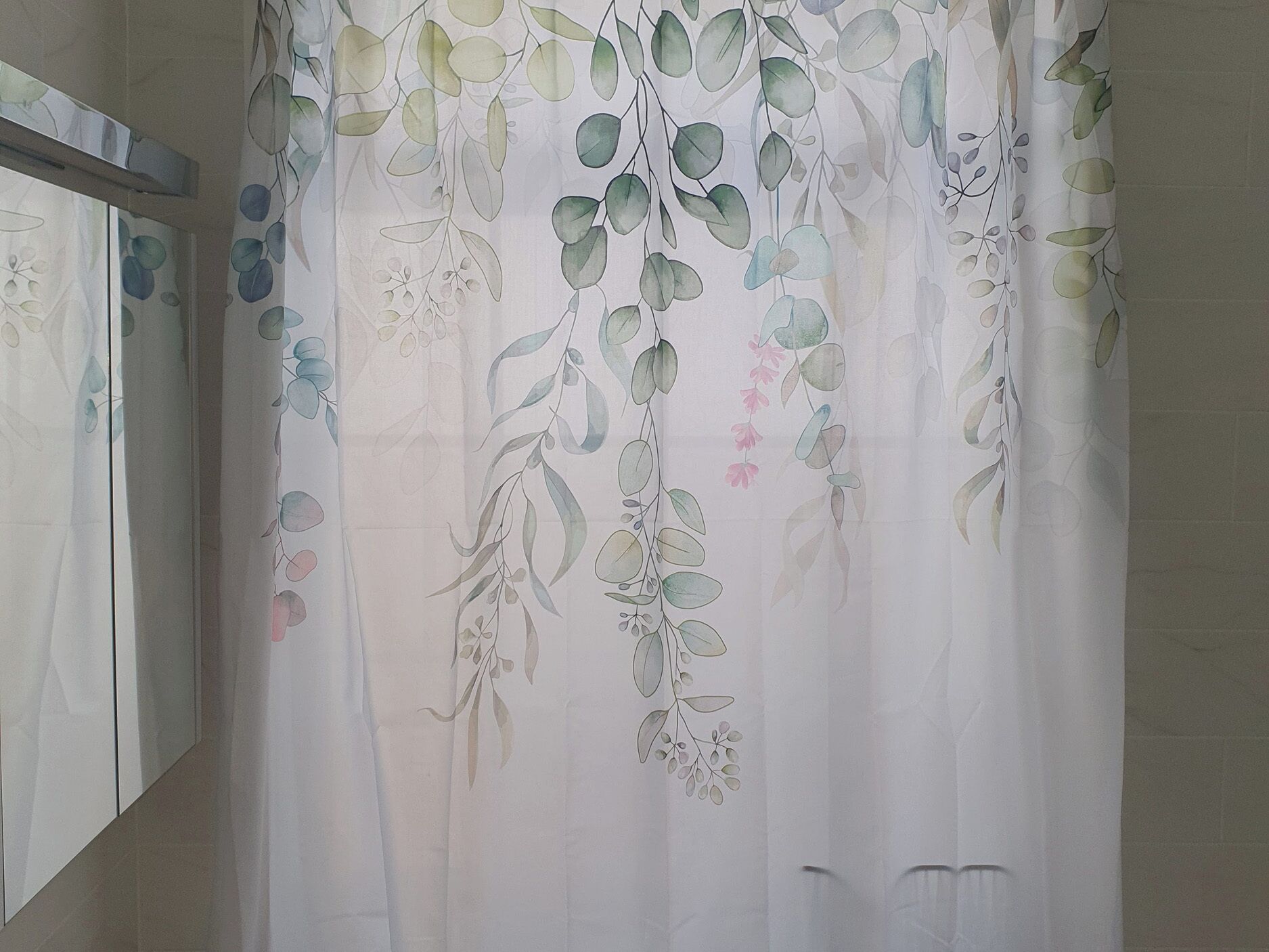 A bathroom with a white shower curtain featuring a floral pattern.