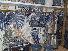 A kitchen with a toaster, two mugs, a kettle, and a decorative backsplash.