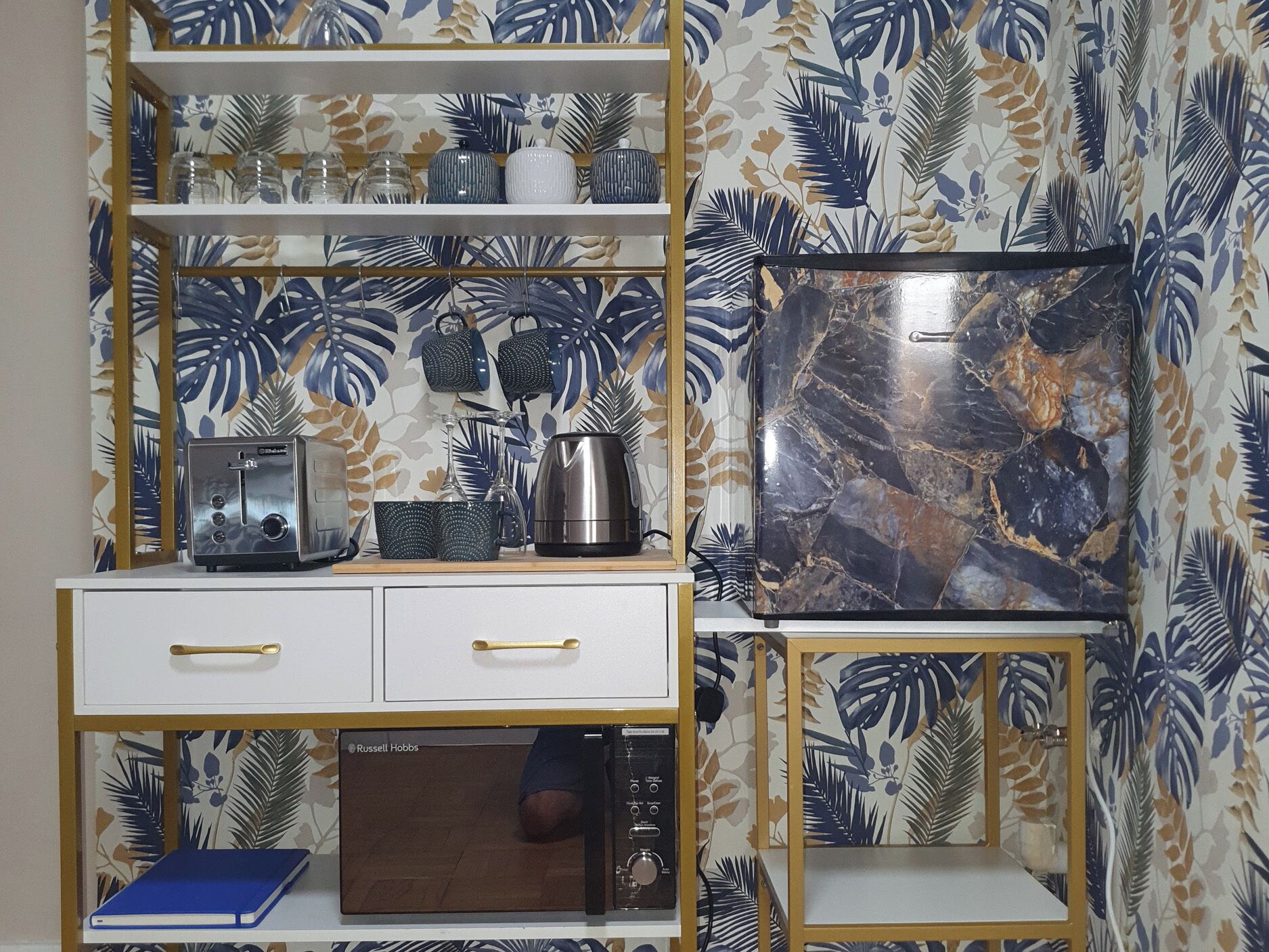 A kitchen with a microwave, toaster, and cabinets, and a television on the wall.