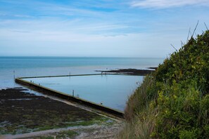 A coastal scene with a pier extending into calm waters, surrounded by vegetation. - Kinamara Ensuite Room (Margate)