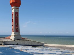 Un faro con el nombre 'LIDO' en su lateral, cielo despejado y mar en calma.