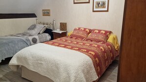 A bedroom with two beds, a nightstand, a lamp, and framed pictures on the wall. - "African" Room, ideal for sporting events at the Le Mans circuit (Le Mans)