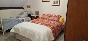 Ein Schlafzimmer mit zwei Betten, einem Nachttisch, einer Lampe und gerahmten Bildern an der Wand.