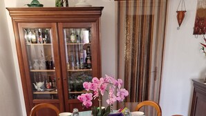 A dining table set with various dishes, a vase of pink flowers, and a cabinet with glass doors in the background. - "African" Room, ideal for sporting events at the Le Mans circuit (Le Mans)