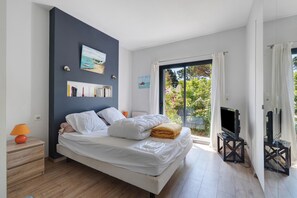 Um quarto moderno com cama, mesa de cabeceira e um suporte de TV com televisão de tela plana.