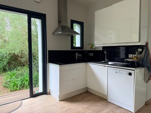 A modern kitchen with white cabinets, a black countertop, and a dishwasher. - Holiday Home 'Aux Jolis Bambous, Garden' with Private Terrace and Garden (Pornic)