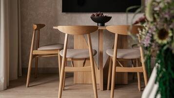 Un comedor con una mesa redonda de madera y cuatro sillas a juego, un cuenco negro sobre la mesa y una planta en primer plano.