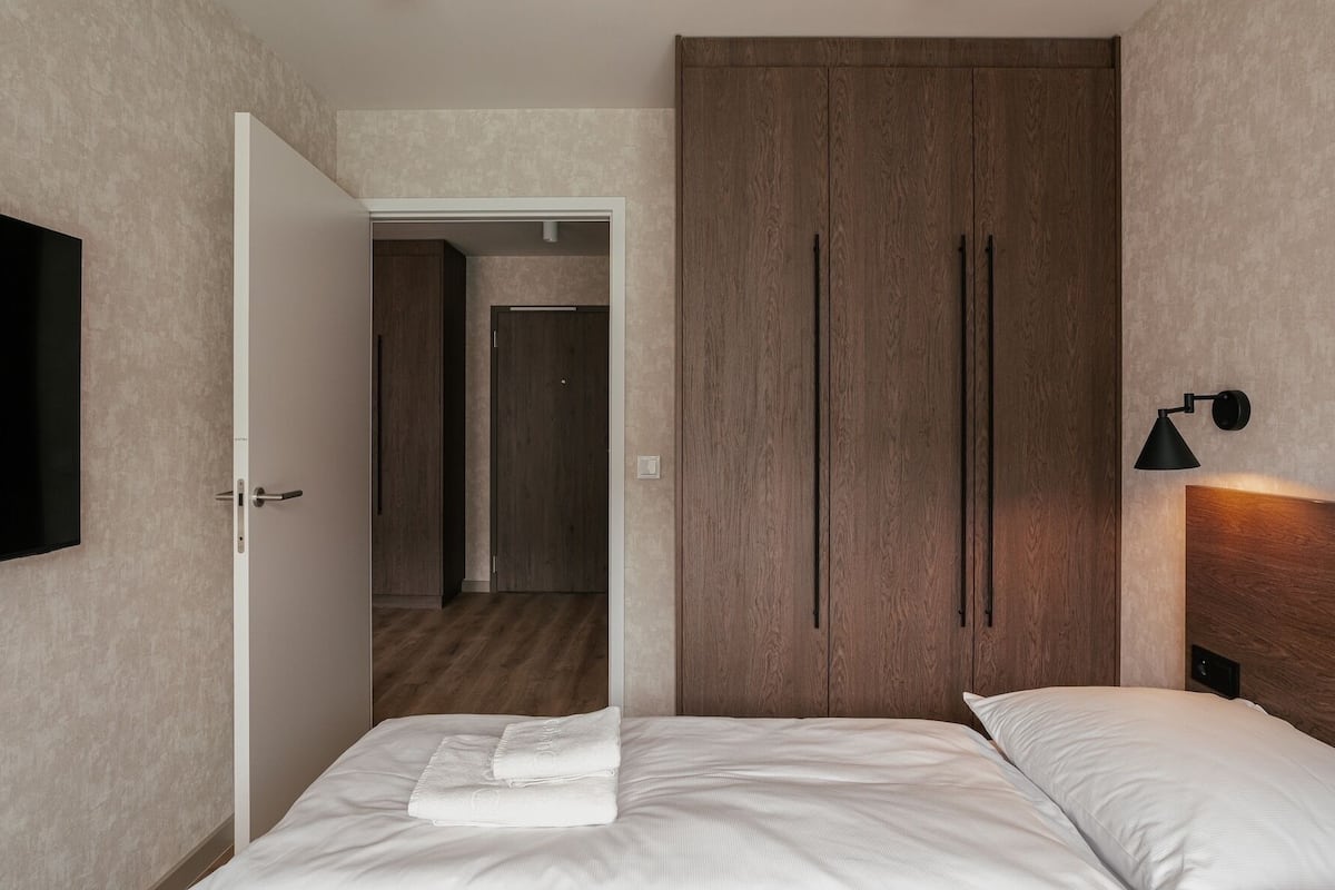 Ein Hotelzimmer mit Bett, Fernseher, Kleiderschrank und Wandlampe.