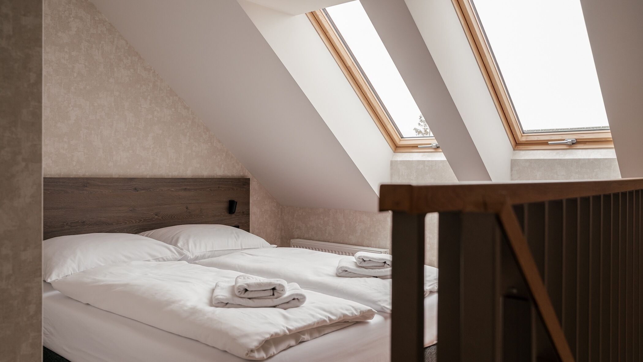 A bedroom with two beds, a sloped ceiling, and skylights.
