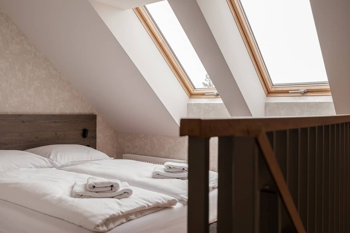 Ein Schlafzimmer mit zwei Betten, einer geneigten Decke und Dachfenstern.