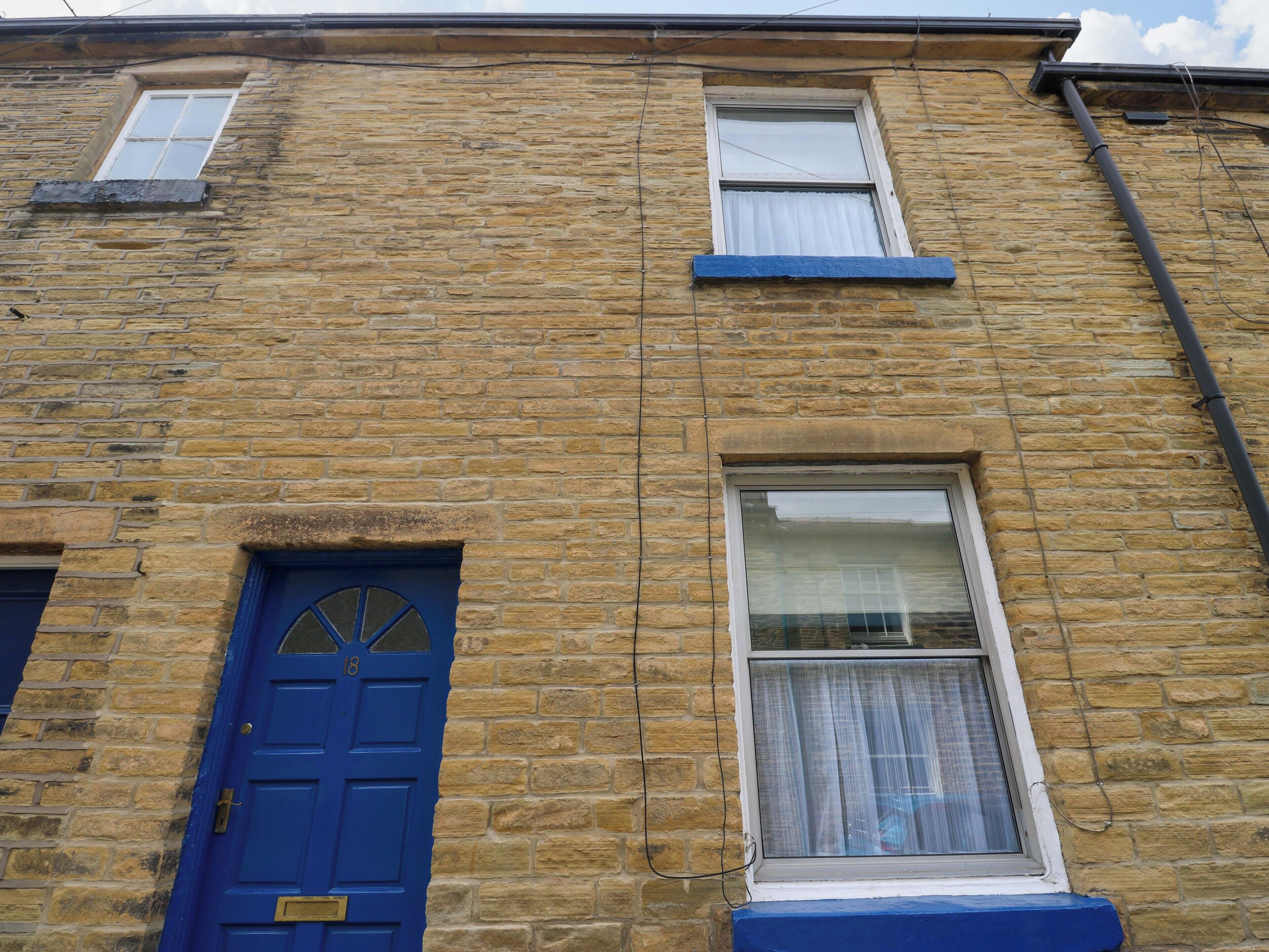 A stone building with a blue door and two windows.