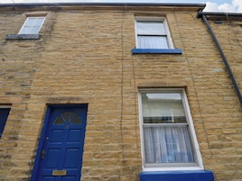 A stone building with a blue door and two windows.