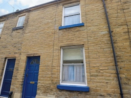A two-story building with stone walls, blue doors, and white-framed windows.