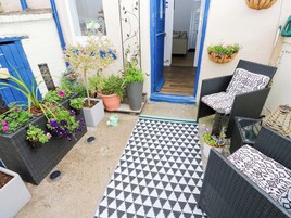 A patio with outdoor furniture, potted plants, and a patterned rug.