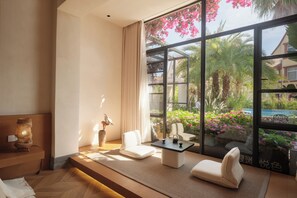 A modern room with a large window, a sofa, a small table, and a decorative lamp.