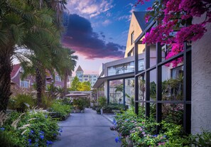 A courtyard with potted plants, a pathway, and a building with large windows and balconies.
