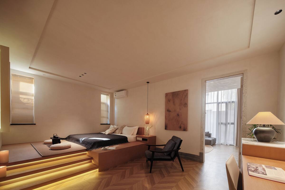 A modern hotel room with a bed, seating area, and a desk.