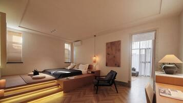 A modern hotel room with a bed, seating area, and a desk.
