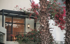A building with large windows, a balcony, and flowering plants.