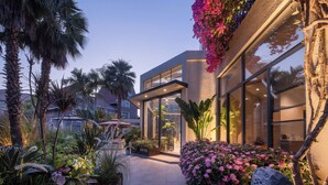 Un edificio moderno con amplios ventanales, un sendero y abundante vegetación.
