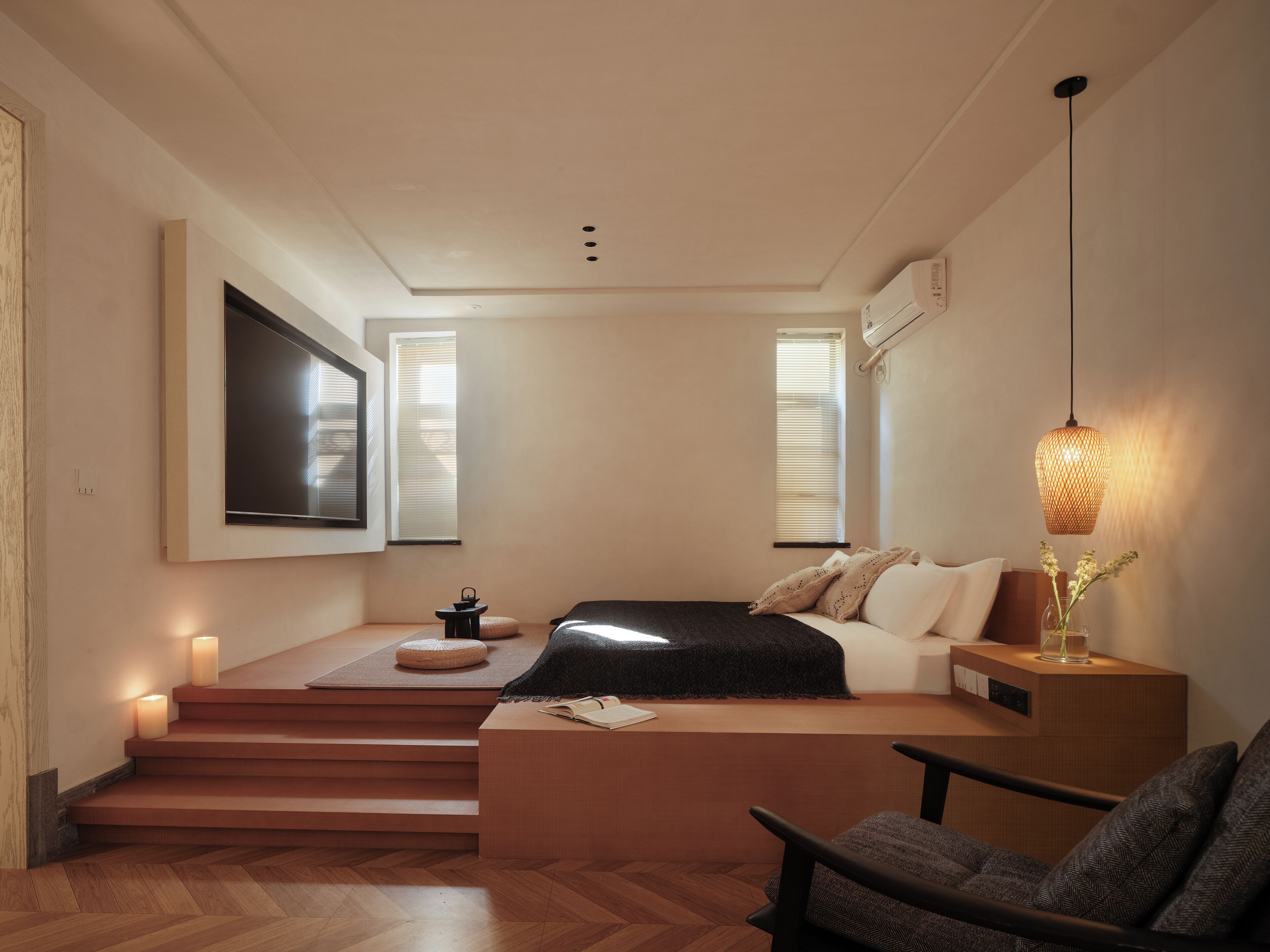 A modern bedroom with a bed, a chair, a small table, a TV, and a window.