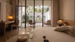 Habitación de hotel con cama, escritorio, silla y vistas al exterior.