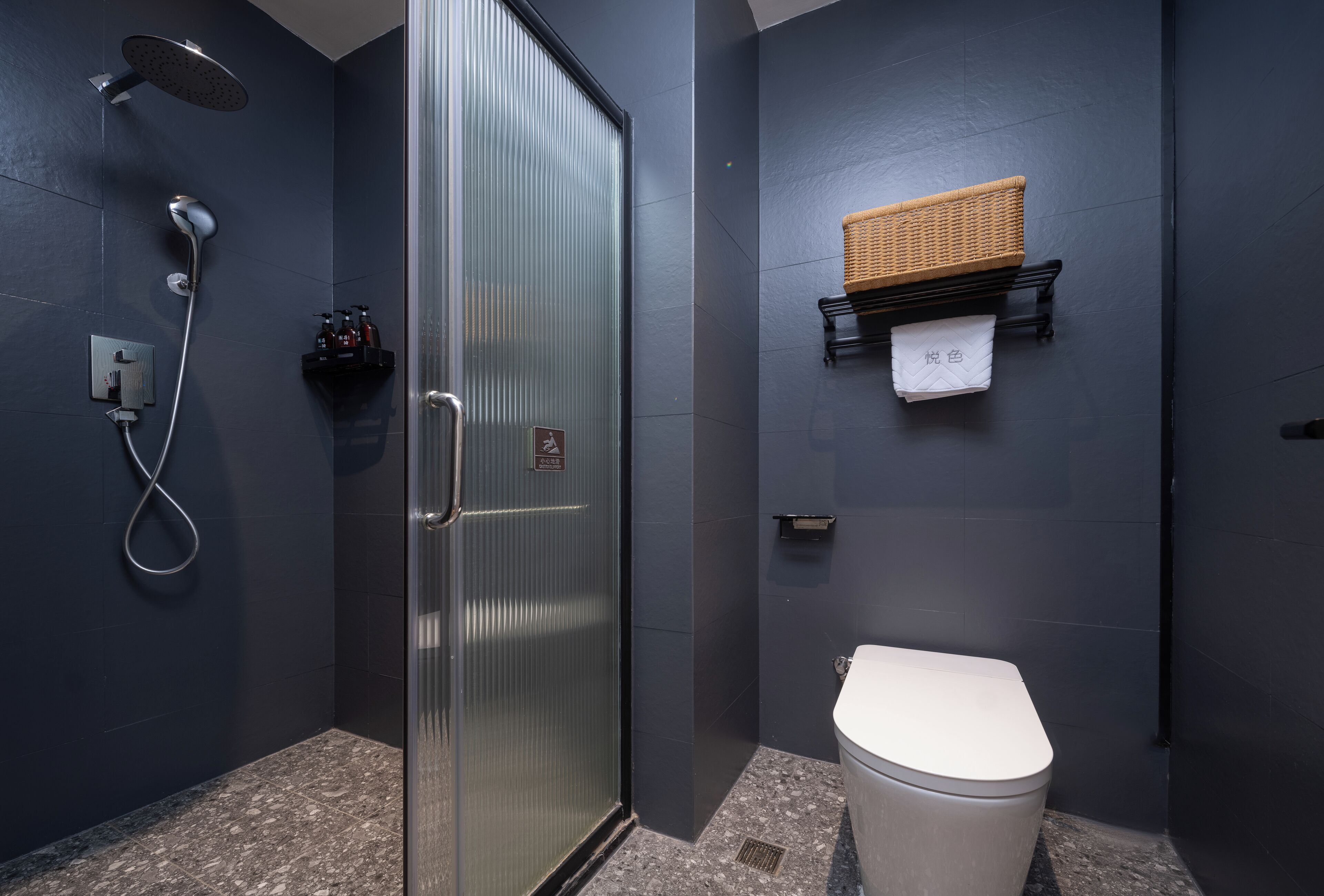 A modern bathroom with a glass-enclosed shower, a toilet, and a towel rack.