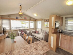 Un espacio habitable compacto con comedor, sofá, cocina y una lámpara colgante.