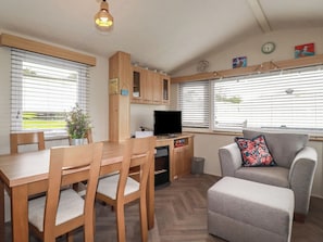 Un espacio habitable compacto con una mesa de comedor, sillas, un sofá, un televisor y una pequeña cocina.