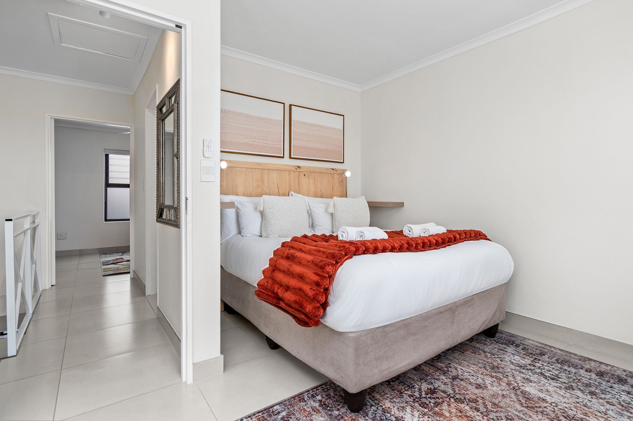 A modern bedroom with a bed, a headboard, a nightstand, and a large window.