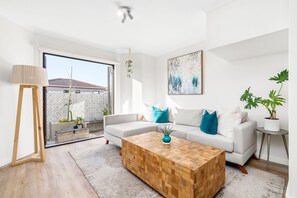 A modern living room with a sofa, coffee table, and potted plants. - 42 Kronenbosch at West Beach (Cape Town)